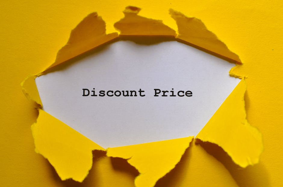 A close-up of a yellow paper surface with a tear revealing a white inner layer, creating an irregular opening. Inside the torn area, a white piece of paper is visible with the words 'Discount Price' printed in black, typewriter-style font. The edges of the tearing are uneven and jagged, with some parts curling outward slightly. The photograph's lighting highlights the texture of the yellow paper, which appears smooth but with torn, rough edges. This image visually suggests themes of discounts, savings, or special offers, and may be relevant for a content piece about cost-effective waste management or private rubbish clearance services in a professional context, such as related to independent rubbish removal and alternative waste handling solutions. The environment appears to be a flat surface, with no additional objects or background elements visible, focusing solely on the torn paper and the message within.